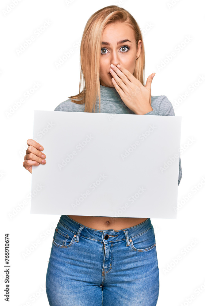 Beautiful caucasian woman holding blank empty banner covering mouth with hand, shocked and afraid for mistake. surprised expression Beautiful caucasian woman holding blank empty banner covering mouth with hand, shocked and afraid for mistake. surprised expression