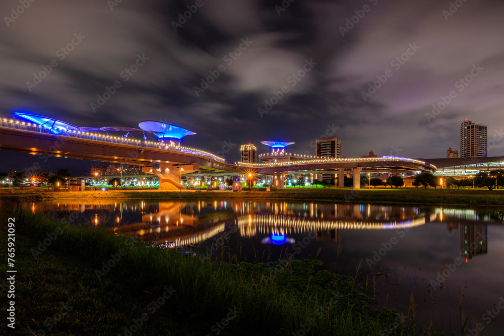 Fototapeta premium Amazing night scenery and reflections in an early summer evening near the Sanchong Station of Taoyuan Airport MRT in the New Taipei City Metropolitan Park.