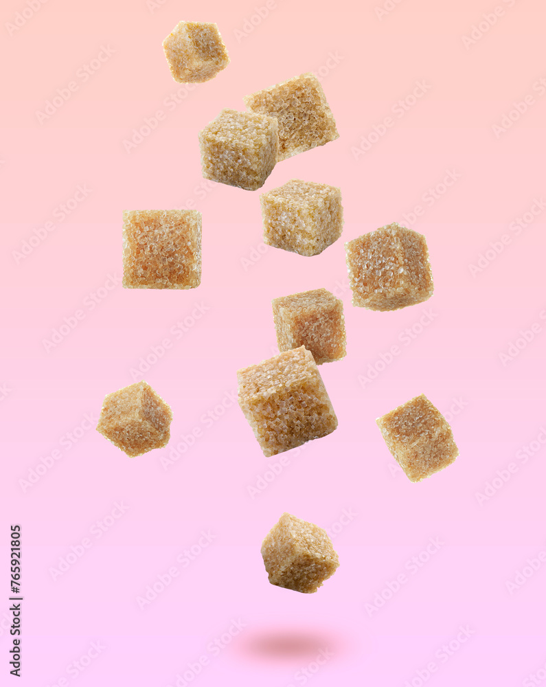 Brown cane sugar cubes falling on color gradient background Brown cane sugar cubes falling on color gradient background