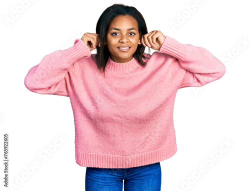 Beautiful hispanic woman wearing casual winter sweater smiling pulling ears with fingers, funny gesture. audition problem