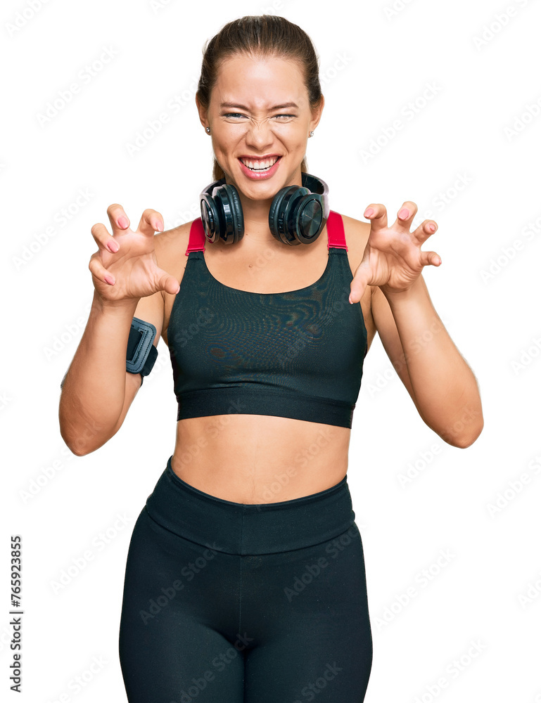 Beautiful blonde woman wearing gym clothes and using headphones smiling funny doing claw gesture as cat, aggressive and sexy expression Beautiful blonde woman wearing gym clothes and using headphones smiling funny doing claw gesture as cat, aggressive and sexy expression
