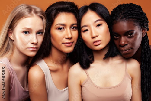young pretty african and caucasian women posing cheerful together on brown background