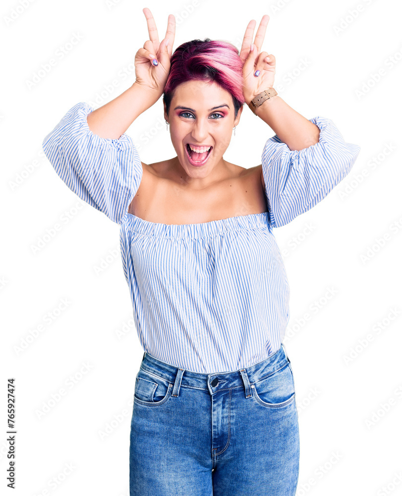Young beautiful woman with pink hair wearing casual clothes posing funny and crazy with fingers on head as bunny ears, smiling cheerful