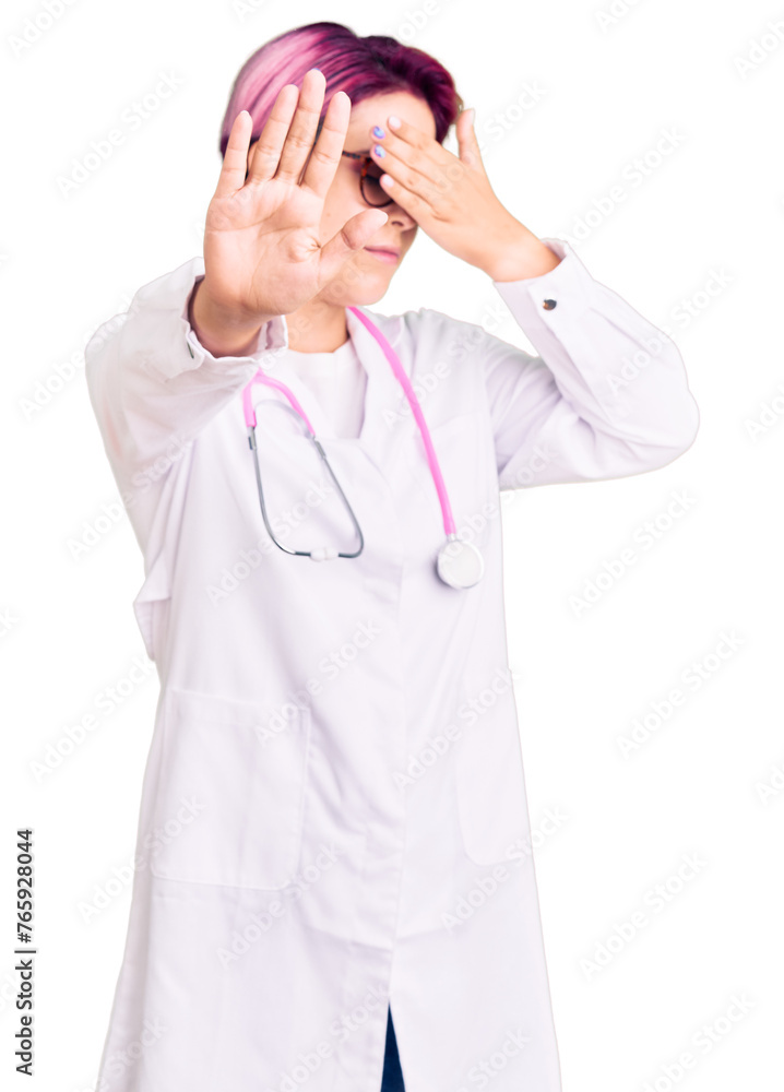 Young beautiful woman with pink hair wearing doctor uniform covering eyes with hands and doing stop gesture with sad and fear expression. embarrassed and negative concept. Young beautiful woman with pink hair wearing doctor uniform covering eyes with hands and doing stop gesture with sad and fear expression. embarrassed and negative concept.