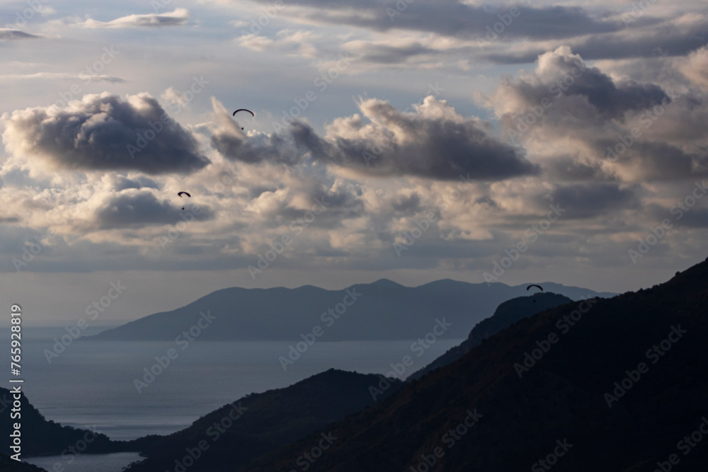 Landscape photo with mountains, sea, sky, clouds and paratroopers in the background