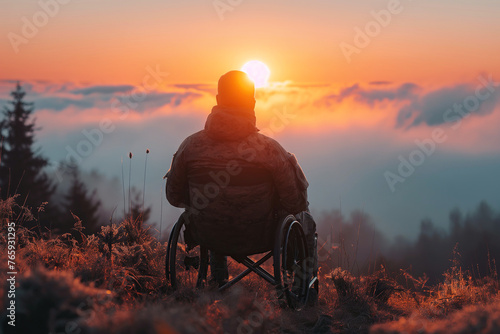 back of disabled military man in invalid wheelchair in nature at sunset