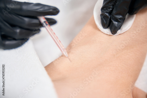Close up partial of female cosmetologist doing armpit beauty injection of woman