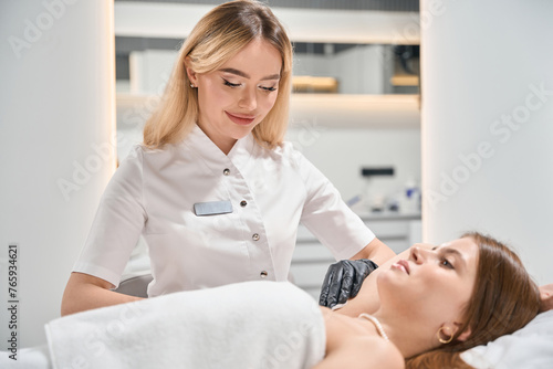 Female beautician doing cosmetological procedure of young caucasian woman