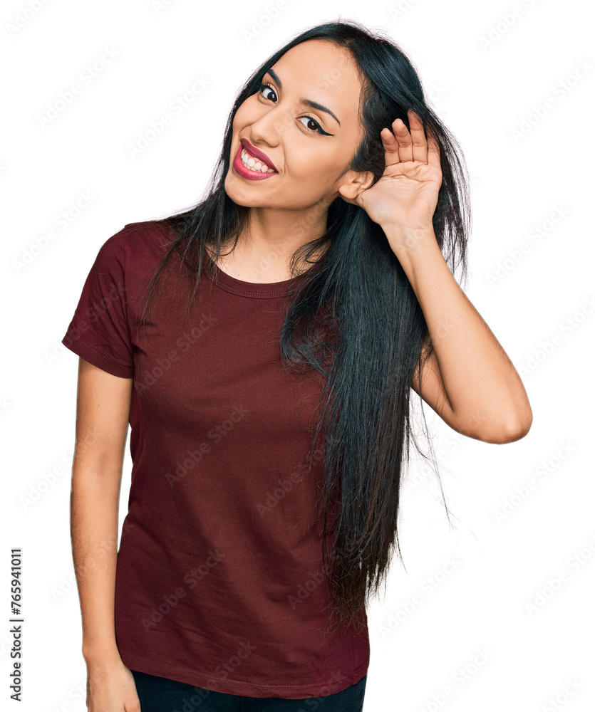 Young hispanic girl wearing casual t shirt smiling with hand over ear listening an hearing to rumor or gossip. deafness concept. Young hispanic girl wearing casual t shirt smiling with hand over ear listening an hearing to rumor or gossip. deafness concept.