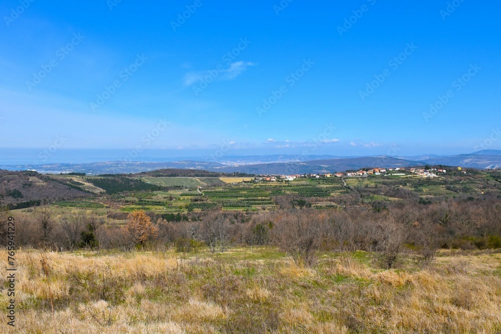 View of landscape in Istria with Marezige village at the top of a ridge and Adriatic sea in the background in Littoral, Slovenia