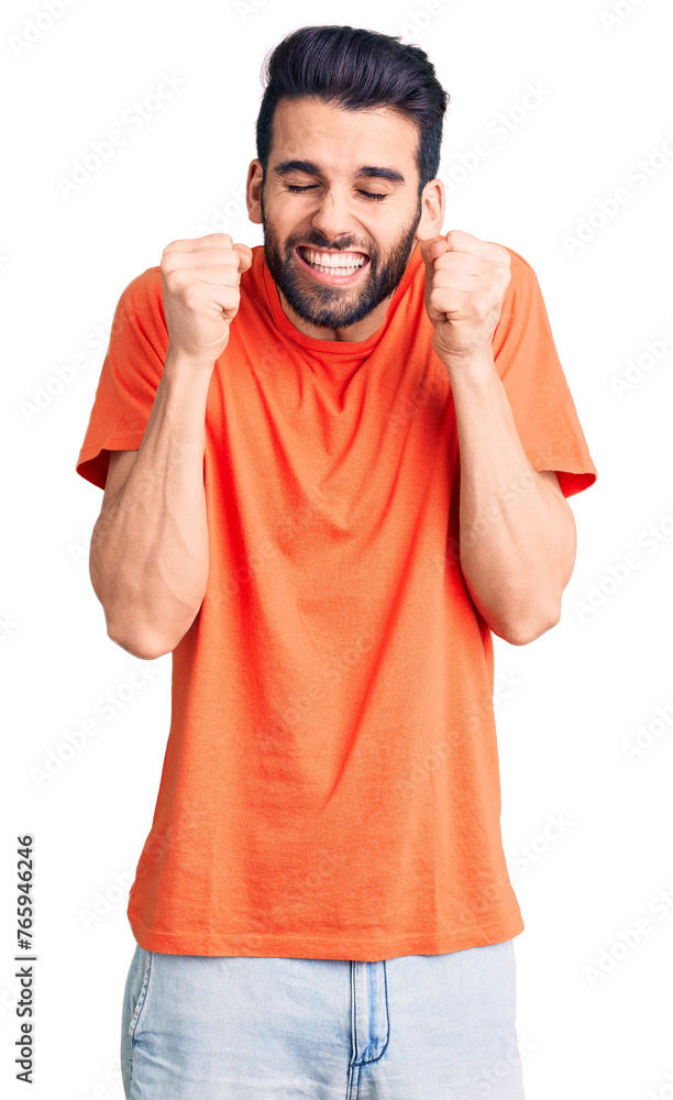 Young handsome man with beard wearing casual t-shirt excited for success with arms raised and eyes closed celebrating victory smiling. winner concept. Young handsome man with beard wearing casual t-shirt excited for success with arms raised and eyes closed celebrating victory smiling. winner concept.