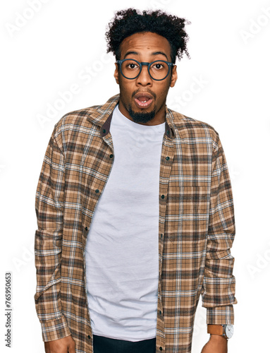 Young african american man with beard wearing casual clothes and glasses afraid and shocked with surprise and amazed expression, fear and excited face.