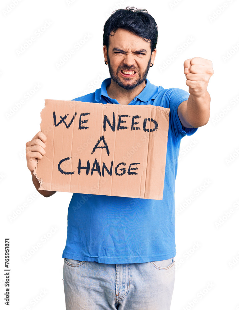 Young hispanic man holding we need a change banner annoyed and frustrated shouting with anger, yelling crazy with anger and hand raised Young hispanic man holding we need a change banner annoyed and frustrated shouting with anger, yelling crazy with anger and hand raised