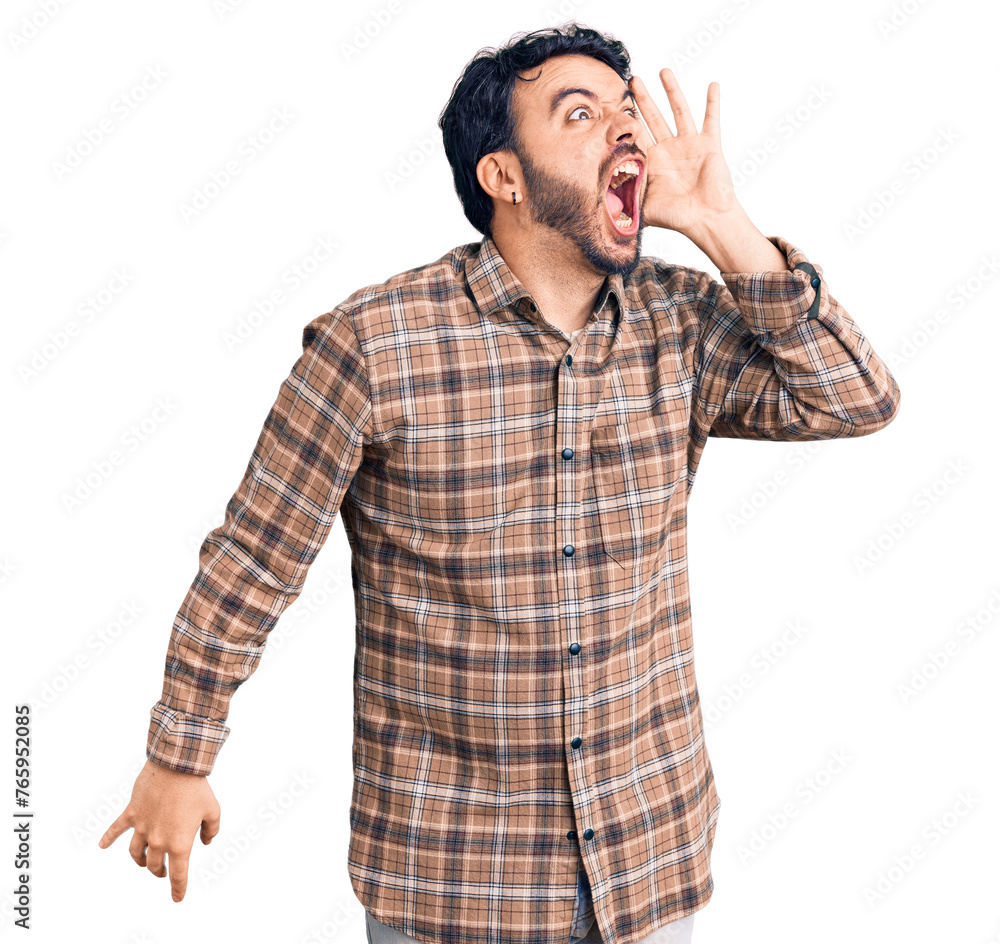 Young hispanic man wearing casual clothes shouting and screaming loud to side with hand on mouth. communication concept. Young hispanic man wearing casual clothes shouting and screaming loud to side with hand on mouth. communication concept.