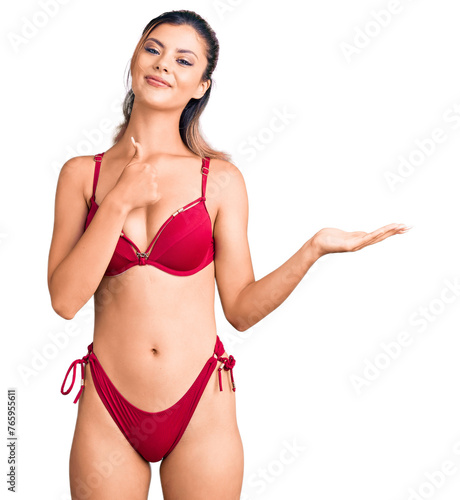 Young beautiful woman wearing bikini showing palm hand and doing ok gesture with thumbs up, smiling happy and cheerful © Krakenimages.com