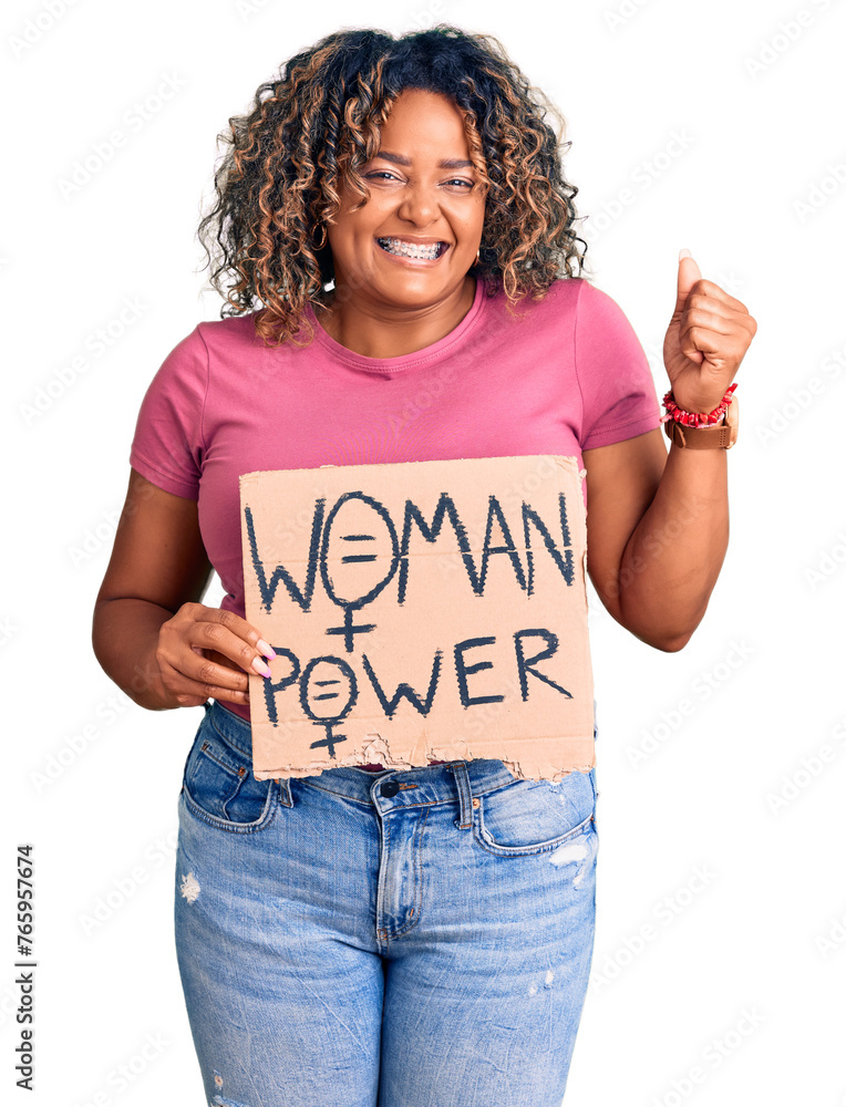 Young african american plus size woman holding woman power banner screaming proud, celebrating victory and success very excited with raised arms