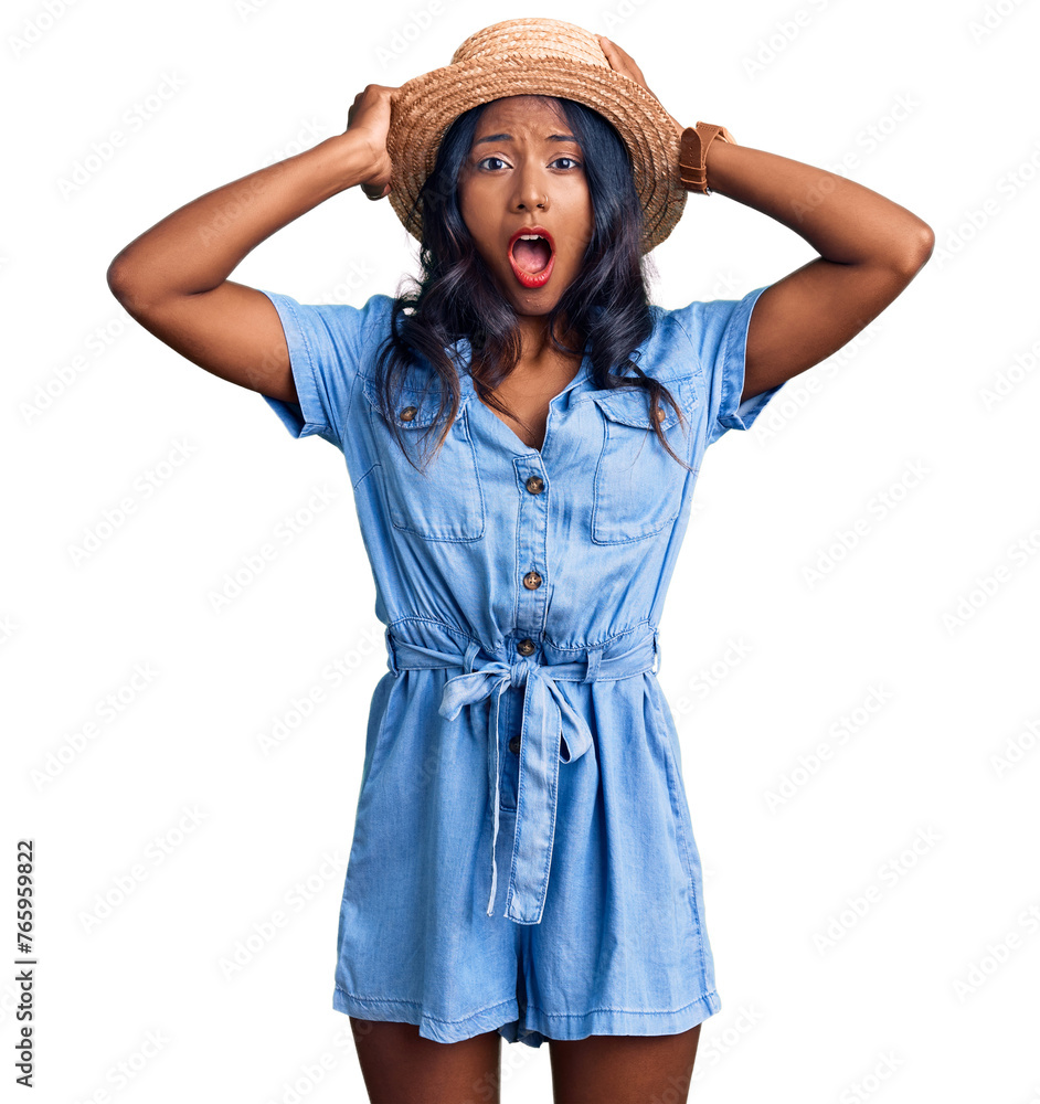 Young indian girl wearing summer hat crazy and scared with hands on head, afraid and surprised of shock with open mouth Young indian girl wearing summer hat crazy and scared with hands on head, afraid and surprised of shock with open mouth