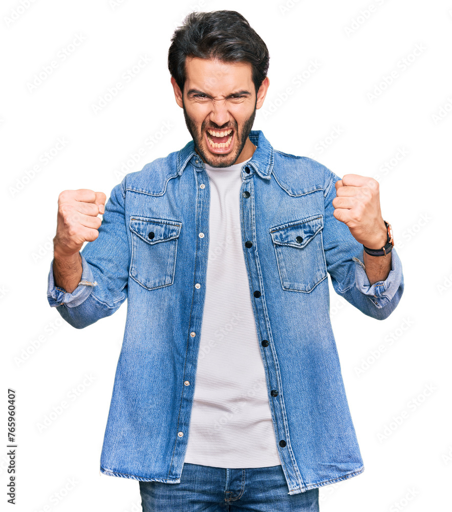 Young hispanic man wearing casual clothes angry and mad raising fists frustrated and furious while shouting with anger. rage and aggressive concept. Young hispanic man wearing casual clothes angry and mad raising fists frustrated and furious while shouting with anger. rage and aggressive concept.