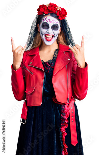 Woman wearing day of the dead costume over background shouting with crazy expression doing rock symbol with hands up. music star. heavy concept.