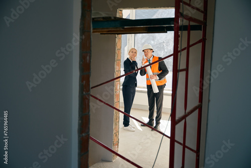 Male contractor and female employee standing and looking upside
