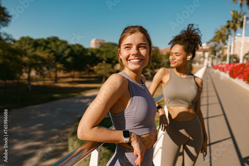 Smiling female sportswomen have a rest after morning jogging outdoors and looks away