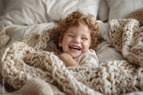 Happy kid lying on bed laughing and playing