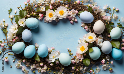 A spring wreath adorned with pastel Easter eggs and white flowers, green leaves, branches, blooming with the colors of the season, isolated on light blue background, flat lay, top view, copy space