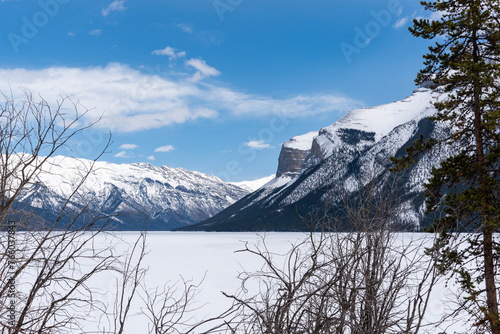 Views from Lake Minnewanka in Banff National Park during spring time with snow capped mountain peaks. Landscape, tourism, road trip shot. 