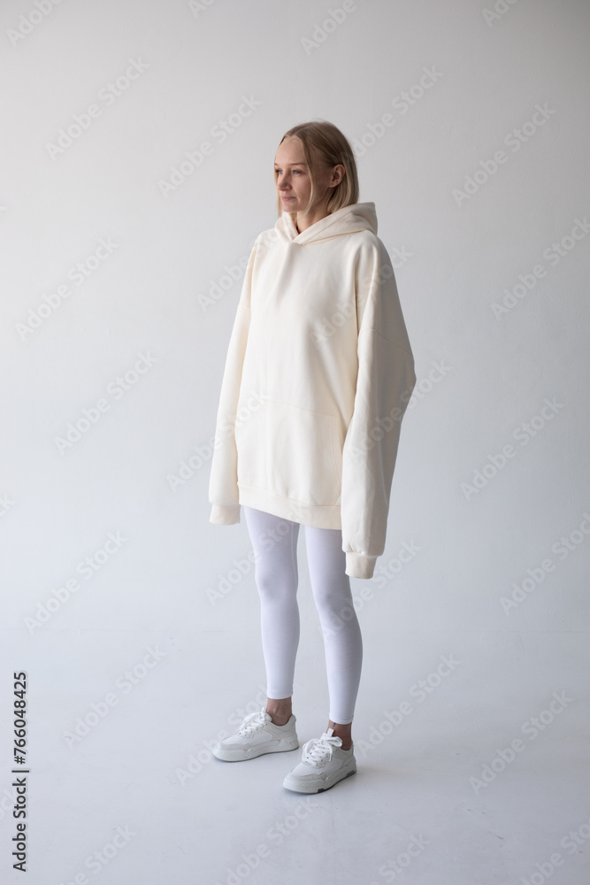 Blonde girl in a white hoodie and tights posing on a white background Blonde girl in a white hoodie and tights posing on a white background