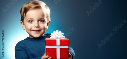 Holiday Surprise: The boy smilingly holds a festively decorated red gift box, conveying a sense of joy and holiday anticipation. friendship day, sister's day, brother's day. photo