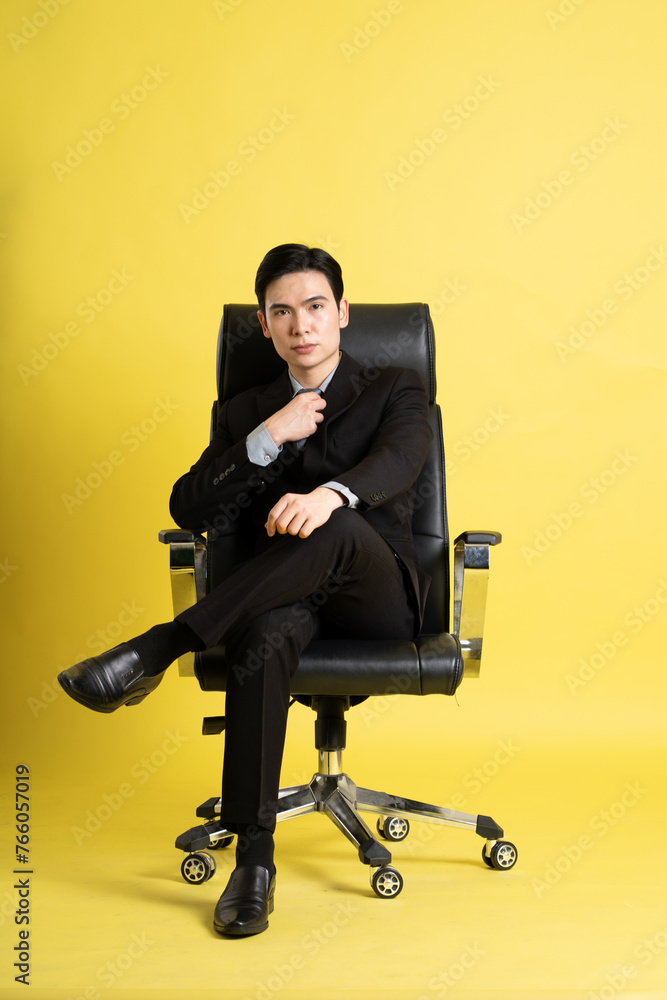 Portrait of Asian male businessman. wearing a suit and posing on a yellow background Portrait of Asian male businessman. wearing a suit and posing on a yellow background