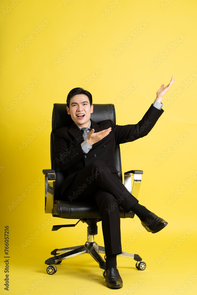 Portrait of Asian male businessman. wearing a suit and posing on a yellow background Portrait of Asian male businessman. wearing a suit and posing on a yellow background