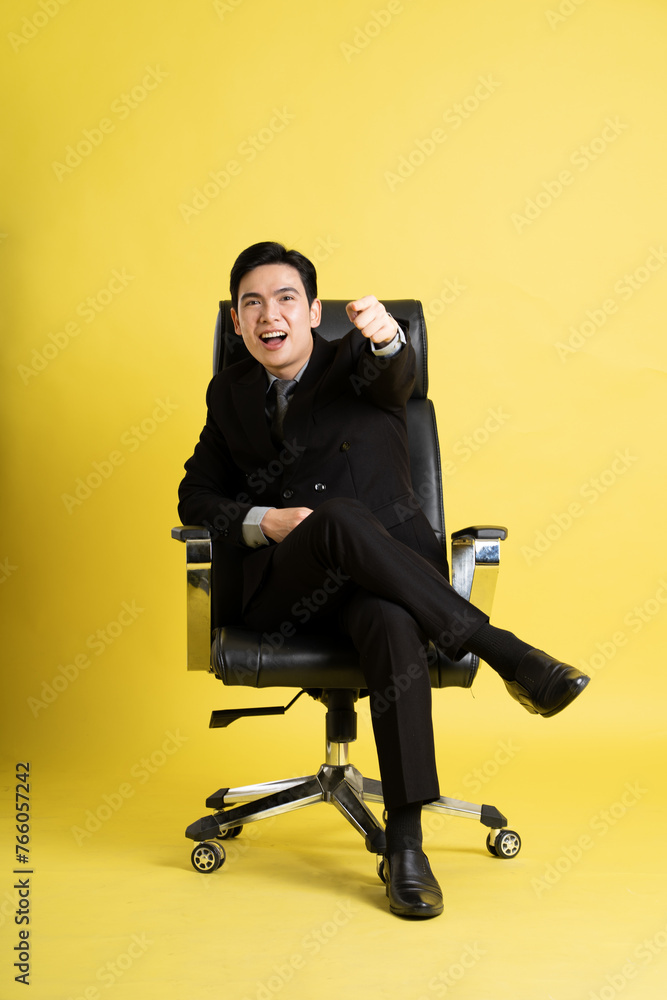 Portrait of Asian male businessman. wearing a suit and posing on a yellow background Portrait of Asian male businessman. wearing a suit and posing on a yellow background