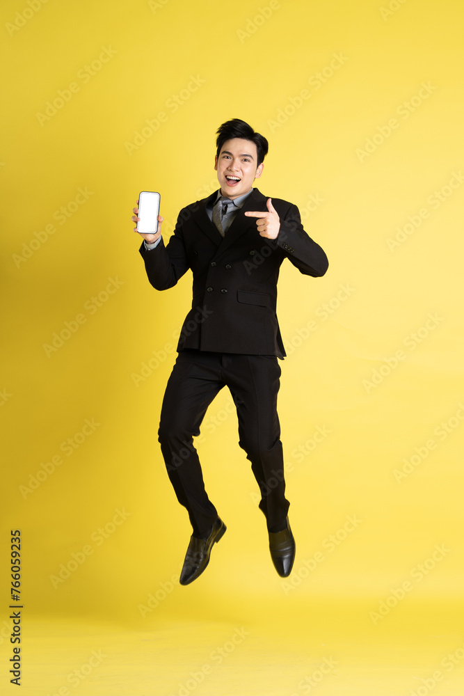 Portrait of Asian male businessman. wearing a suit and posing on a yellow background Portrait of Asian male businessman. wearing a suit and posing on a yellow background