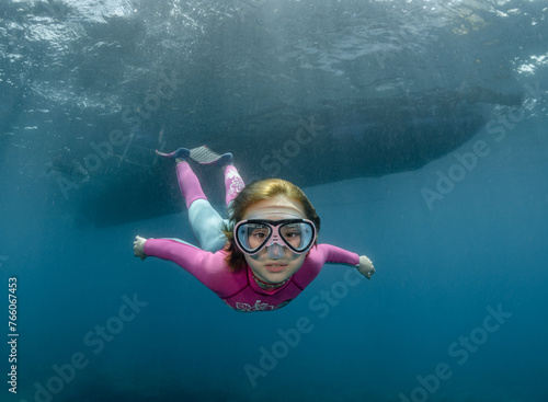 Underwater portrait of a child wearing a diving mask in the sea in the rays of the sun (ID: 766067453)