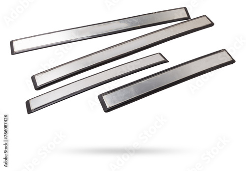 A four of black plastic decorative door sills in an automobile parsing for sale or repair in a workshop on a white isolated background in a photo studio.
