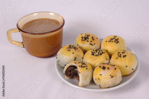 Tau Sar Piah with Sweet green been and Sweet black seeds and salted egg on a white background with a cup of hot milk tea photo