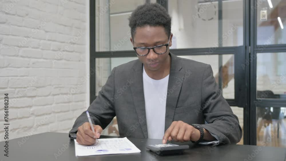 Young African Man Doing Calculations for Paperwork Young African Man Doing Calculations for Paperwork