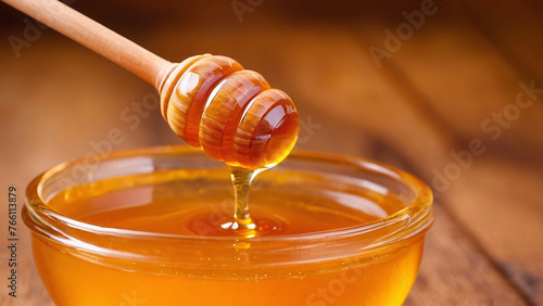 Honey dripping from a wooden honey dipper into a glass bowl
