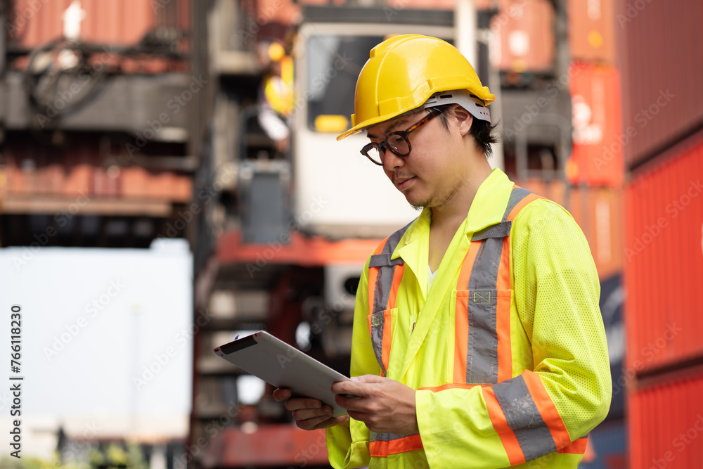Asia logistic engineer man worker or foreman working with tablet computer and forklift container background at container site	