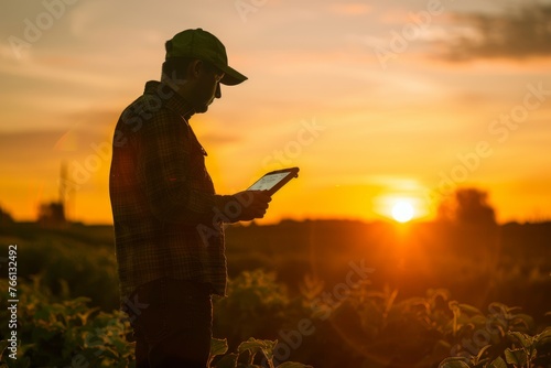Tech-Savvy Farmer Reviewing Data on Tablet During Sunset in Field