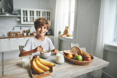Junge Kind Heranwachsender sitzt fröhlich glücklich lächelnd barfuß am Tisch Frühstück zu Hause in hell Ausstattung Kindheit Ernährung Genuß Freude, Start in den Tag, Küche lebensstil frühstücken