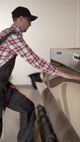 Professional carpet cleaning concept. Laundry worker in cap working on automatic machine for carpet cleaning from dust and dirt photo