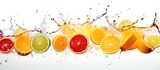 A colorful array of fruits is cascading in a row on a pristine white background, creating a vibrant and artistic display. The liquid splashes add an element of movement and energy to the composition