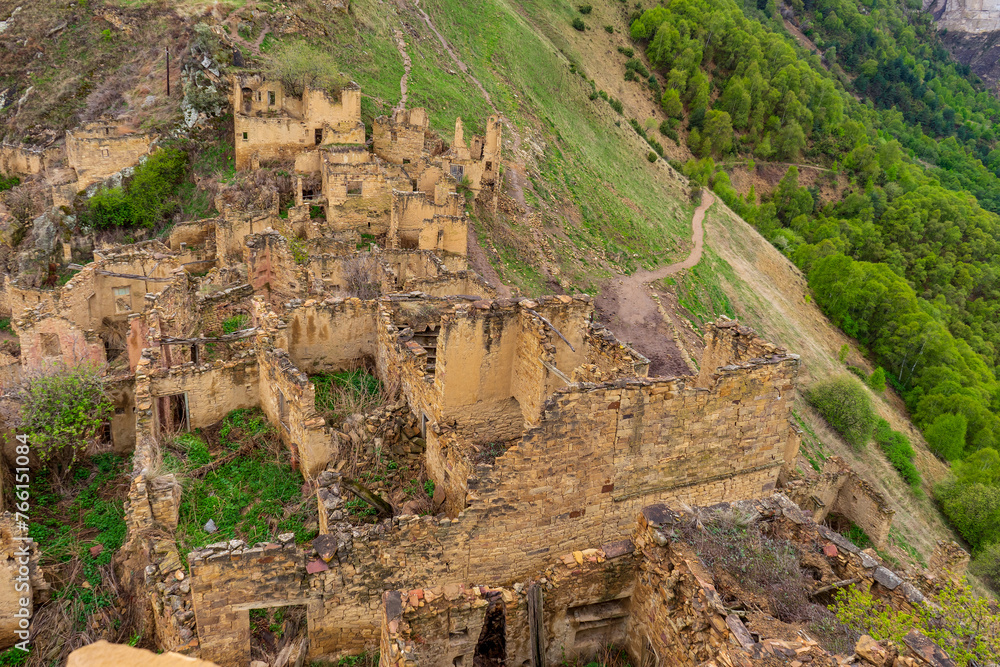 Ruins of ancient settlement in mountains. Ruined mountainous village Gamsutl in Dagestan republic. Old abandoned stone houses and buildings against spring landscape. Caucasian aul, Caucasus, Russia Ruins of ancient settlement in mountains. Ruined mountainous village Gamsutl in Dagestan republic. Old abandoned stone houses and buildings against spring landscape. Caucasian aul, Caucasus, Russia
