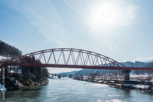 ドローン写真：トラス構造の赤い橋と、晴れた冬の自然