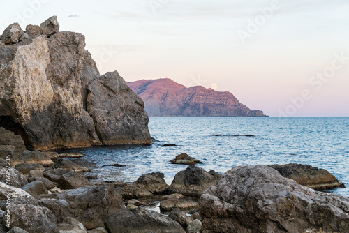 Sudak  Crimea. Moon rise. Cape Rybachy. Mount Meganom in the light of the setting sun