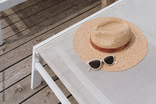 Relaxing and sunbathing concept. Straw hat, sunglasses on sun lounger. Summer vacation holidays at resort