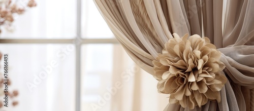 A closeup of a curtain hanging from a window with a beautiful flower attached to it, showcasing the delicate petals and vibrant colors of the flowering plant