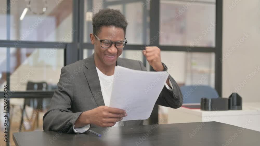 African American Man Celebrating while Reading Documents African American Man Celebrating while Reading Documents